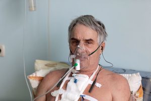 Patient in hospital with oxygen mask wearing BeHear ACCESS hearing headset